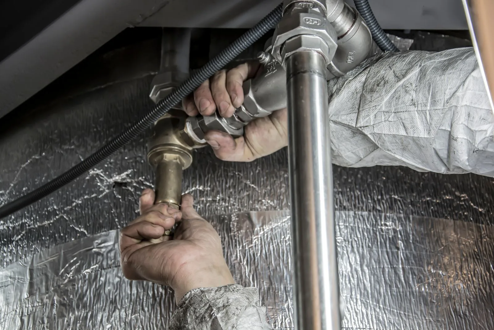 A plumber tightening a pipe fitting during a service call
